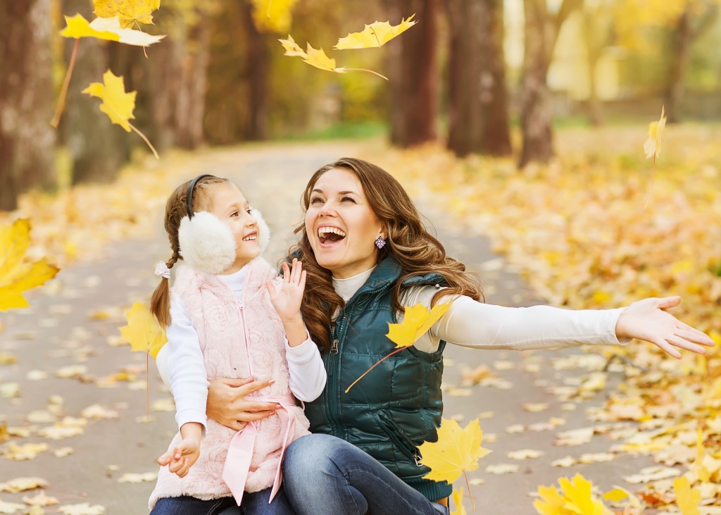 Mother And Daughter Having Fun In The Autumn Park Among The Fall