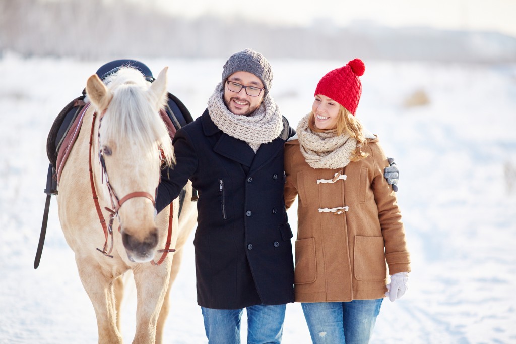Young couple walking with horse in winter day